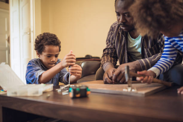 istock Kids assisting their father repairing the shelf 1002107026