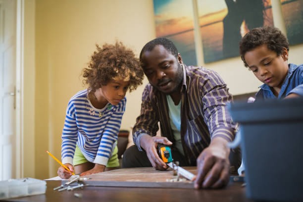 istock Kids assisting their father repairing the shelf 1002107074
