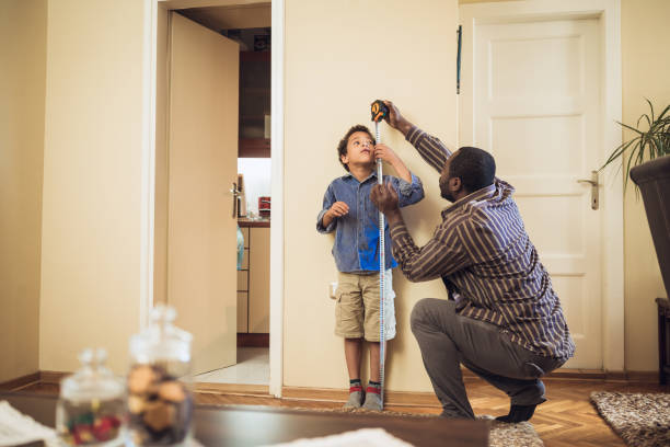 Father measuring sons height Shot of a father measuring his son height against a wall at home human height stock pictures, royalty-free photos & images