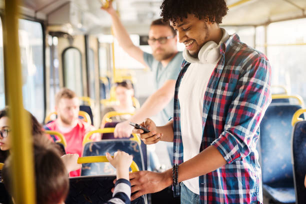 istock Young Afro-American with headset around his neck is looking at his phone while riding in a bus. 1002107554
