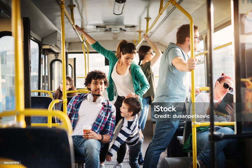 Young mother and her son are training not to fall in a bus full of people. Young mother and her son are trying not to fall in a bus full of people. Bus Stock Photo