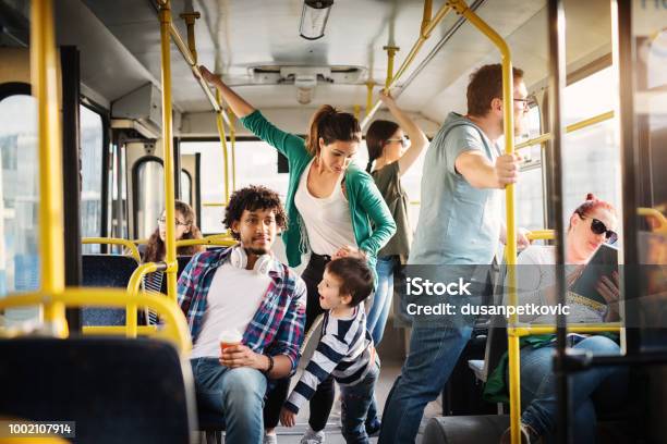 Young Mother And Her Son Are Training Not To Fall In A Bus Full Of People Stock Photo - Download Image Now