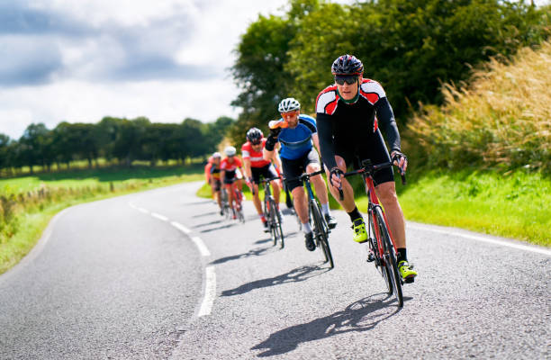 Cyclists racing on country roads. Cyclists racing on country roads on a sunny day in the UK.Cyclists racing on country roads on a sunny day in the UK. cycling stock pictures, royalty-free photos & images