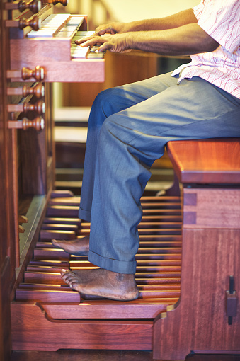 Bare feet and hands of African man organist playing an old wooden organ Dar es Salaam