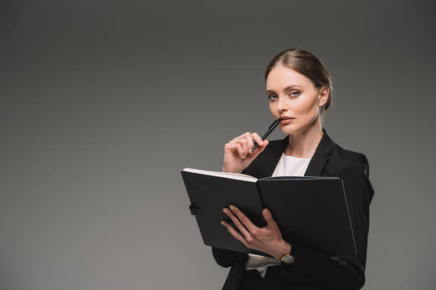 istock thoughtful businesswoman holding textbook isolated on grey background 1002109368
