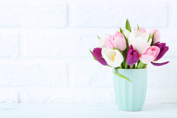 istock Bouquet of tulips in cup on brick wall background 1002112766