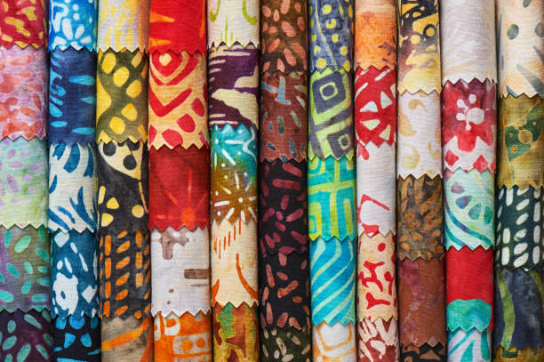 pila di colorati tessuti batik trapuntati come immagine di sfondo vibrante - patch textile stack heap foto e immagini stock