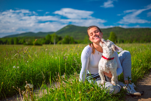 Happy Young Woman Bonding with Her Dog on Meadow.