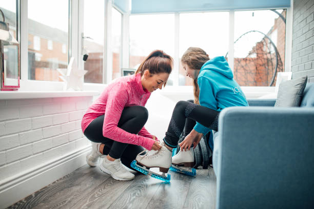 Getting Ready for Ice Skating Lessons Woman is helping her daughter put her figure skates on before she takes her to a skating lesson. single skating stock pictures, royalty-free photos & images