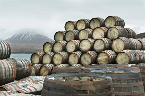 Whisky casks have been stacked up outside Bunnahabhain distillery on the north of the Isle of Islay waiting to be filled with Whisky and transported for storage.