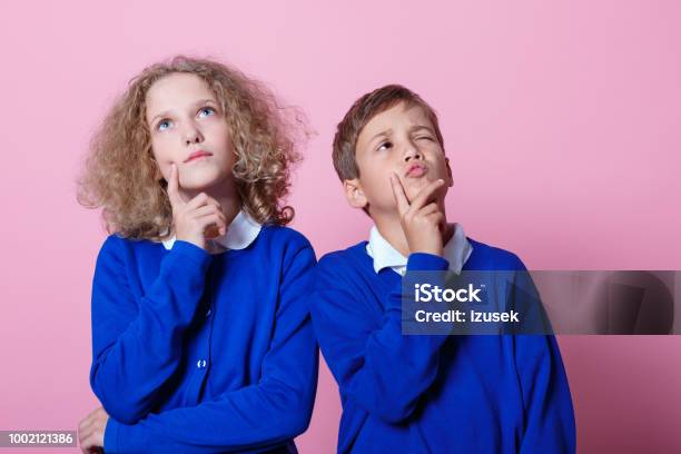 Portrait Of Pensive Cute Schoolboy And Schoolgirl Stock Photo - Download Image Now - Boys, Contemplation, Pink Background