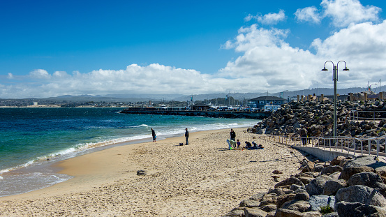 People at the beach in Monterey next to the harbor, California