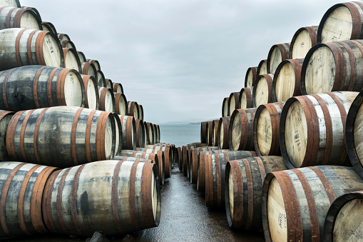 Two large stacks of whisky casks sit outside Bunnahabhain distillery, Isle of Islay, waiting to to be filled with whisky and stored.