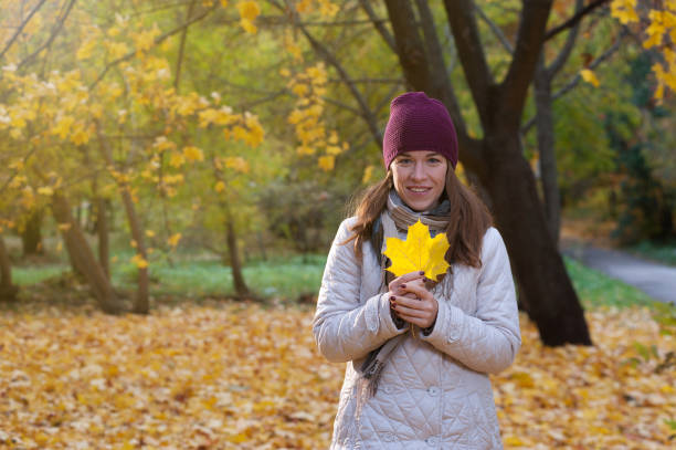 istock Young woman with yellow leaf in autumn park 1002130792