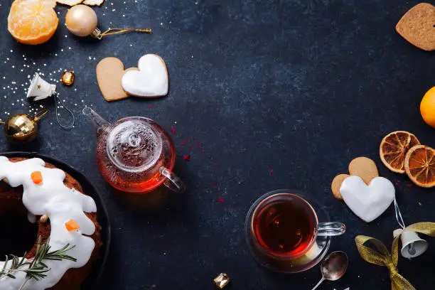 Teatime with heart-shaped ginger cookies, traditional fruitbread and tangerines. Christmas background with festive decoration. Horizontal composition