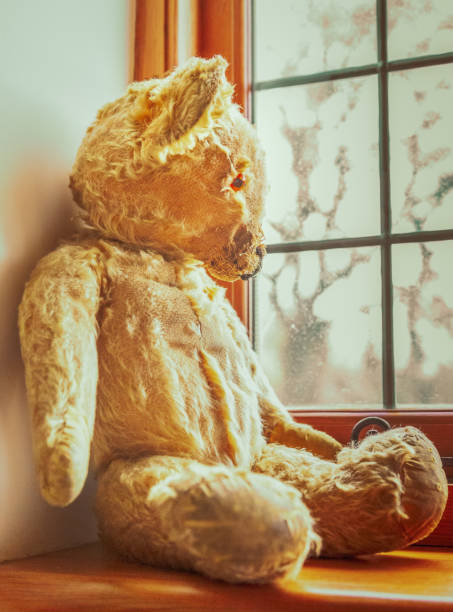istock vintage worn teddy bear toy looking out of a window 1002140098
