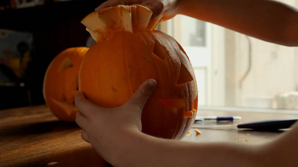 istock Young boy carving and painting a pumpkin for Halloween on a table 1002140358