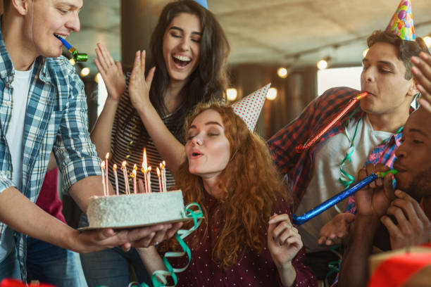 Friends presenting birthday cake to girl Happy birthday girl is blowing candles on holiday cake and making wish, copy space anniversary gifts stock pictures, royalty-free photos & images