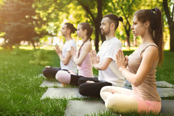 istock Group of people meditating in park 1002145150