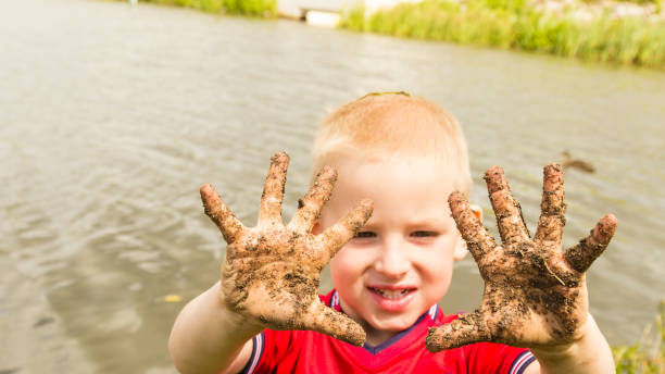 istock Child playing outdoor showing dirty muddy hands. 1002150112
