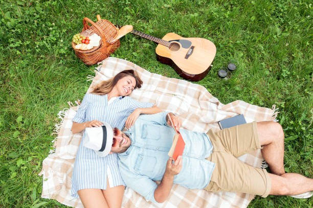 bella giovane coppia sorridente che si gode il loro tempo insieme in un picnic in un parco, leggendo libri e rilassandosi. vista ad angolo alto - 13431 foto e immagini stock