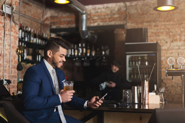 istock Young man sitting at bar counter and using smartphone 1002153256