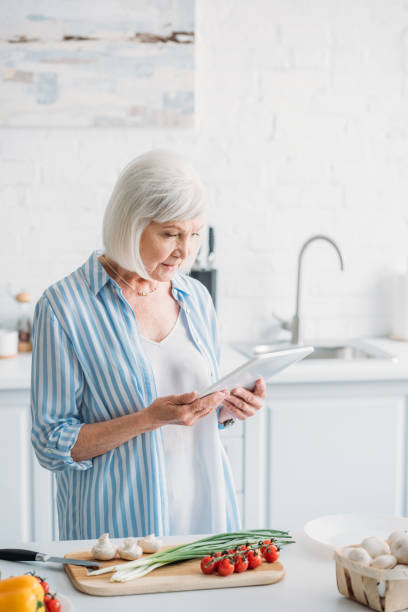 istock senior woman with digital tablet standing at counter with fresh vegetables in kitchen 1002153434