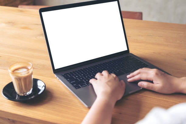 istock Mockup image of a woman using laptop with blank white desktop screen with coffee cup on wooden table 1002153504