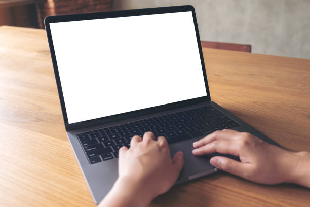 istock Mockup image of a woman using laptop with blank white desktop screen on wooden table 1002153750