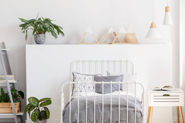 istock Plant and triangles on headboard in teenager's bedroom interior with grey sheets on bed. Real photo 1002158492