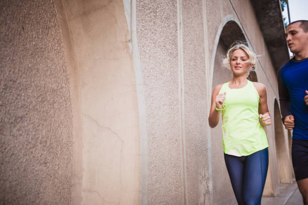 istock Young couple, athletes, jogging together in the urban environment 1002158584