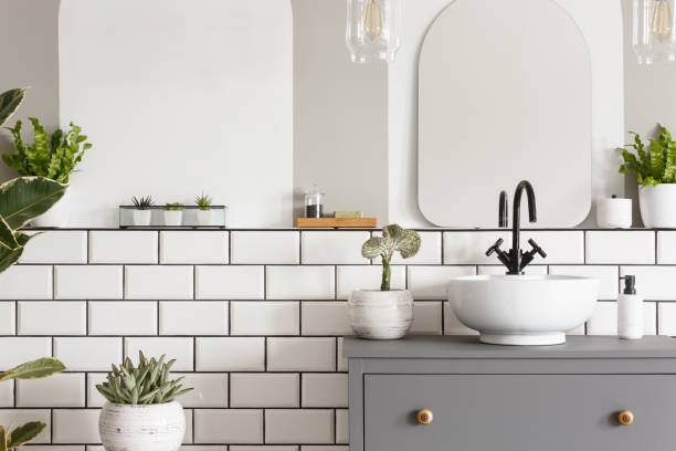 foto real de um coletor em um cupbaord no interior de um banheiro com azulejos, espelho e plantas - bathroom black faucet - fotografias e filmes do acervo