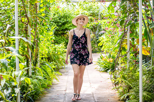 Beautiful woman enjoying beauty of tropical forest, walking on footpath. Surrounded by tropical nature.