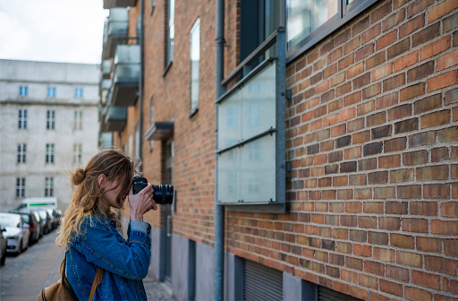 woman with photo camera taking picture of architecture in copenhagen, denmark