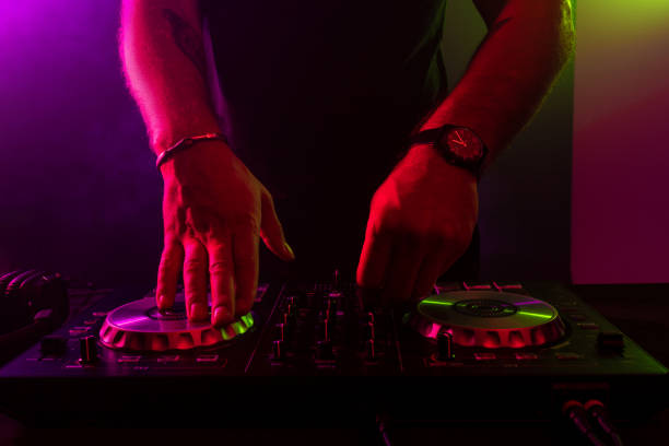 istock Dj mixing on turntables with color light effects. Soft focus on hand. Close-up 1002174860