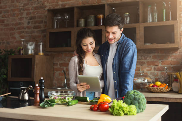istock Beautiful young couple reading recipe on tablet 1002175006