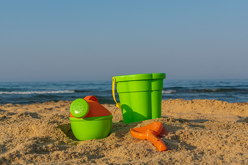 A bucket and shovel in the sand of a beach ,closeup, copy space.