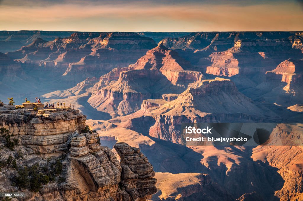 Hikers in Grand Canyon National Park at sunset, Arizona, USA A group of hikers is standing on a steep cliff watching the sun set over famous Grand Canyon in summer, Grand Canyon National Park, Arizona, USA Grand Canyon Stock Photo