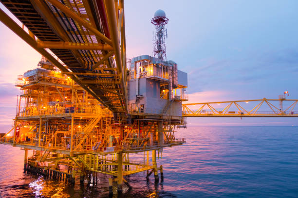 istock Offshore construction platform for exploration and production oil and gas with bridge in evening time for power energy of the world concept. 1002180218