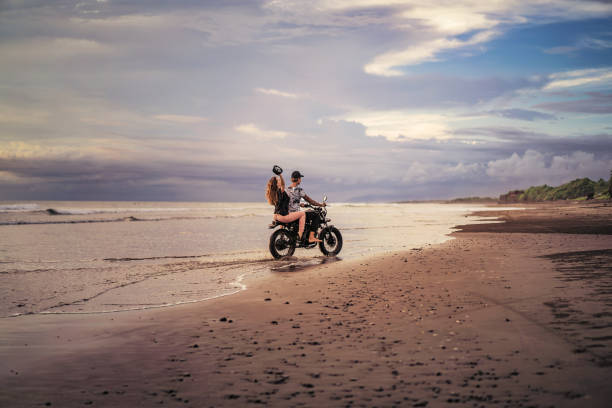 istock couple riding motorcycle on ocean beach during sunrise in summer 1002180384