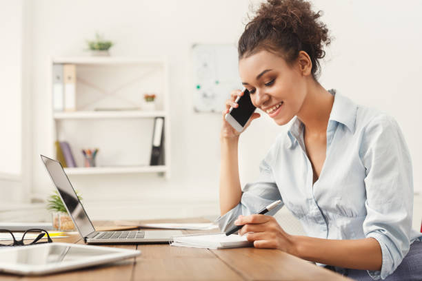 istock Smiling business woman at work talking on phone 1002181156