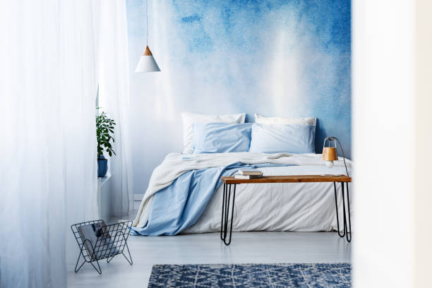 istock Patterned rug and books on the table in blue bedroom interior with pastel pillows on bed 1002181388