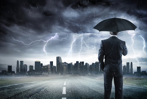 Businessman With Umbrella Looking Storm Over City