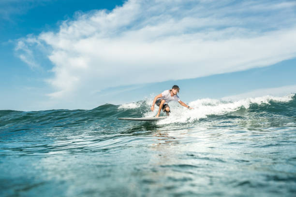 fernblick über männliche surfer wellen im ozean in nusa dua beach, bali, indonesien - bali male beautiful ethnicity stock-fotos und bilder