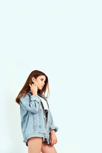 istock A beautiful model in a white T-shirt and jeans clothes posing in the studio on a white background. Lifestyle, fashion, beauty 1002192346