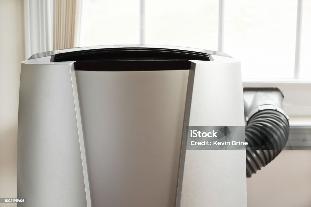 Air Conditioner Portable air conditioner in front of brightly lit window. Air Conditioner Stock Photo