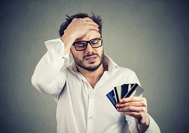 Stressed man having debts with credit card Young bearded man in glasses and shirt holding hand on head in despair having finance debts for credit cards over spend stock pictures, royalty-free photos & images