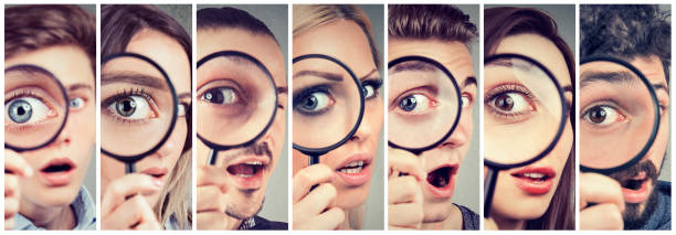 Group of curious women and men looking through a magnifying glass Group of curious young women and men looking through a magnifying glass large eyes stock pictures, royalty-free photos & images