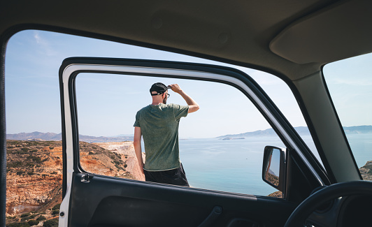 Man enjoying the view from the mounatin road in Milos island (Cyclades, Greece). View from the car.