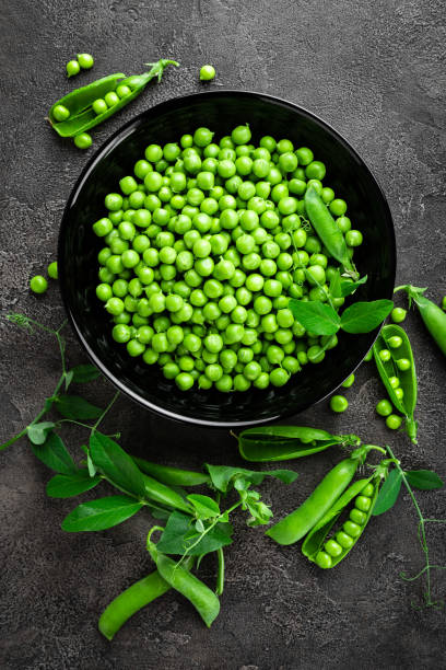 istock Green peas with pods and leaves 1002215840